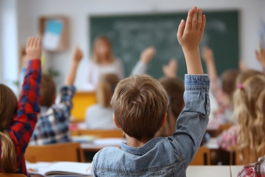 Engaged Elementary School Children with Raised Hands in a Dynamic Classroom Setting