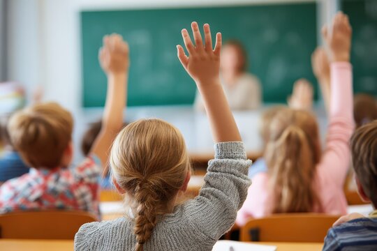 Engaged Elementary School Children with Raised Hands in a Dynamic Classroom Setting