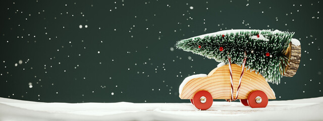 Christmas greeting card design with copy space. Cute wooden toy car carrying fir tree on the roof....