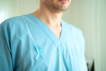 Close up of male doctor wearing medical uniform with blue satin ribbon. November prostate cancer...