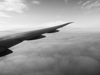 Aile d'un avion volant au-dessus des nuages. Noir et blanc.