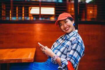 Woman sits smiling with smartphone, leaning sideways in casual joy, enjoying spontaneous moment of...