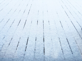 Obraz premium Snow-covered wooden walkway in winter, textured planks under a thin layer of fresh white snow creating a minimalistic clean seasonal background for cold weather and holiday concepts