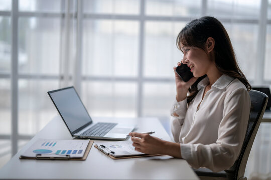 Businesswoman talking on phone and analyzing financial charts in office