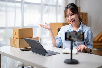 Young asian woman using smartphone for live streaming to sell product online