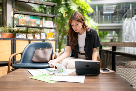 Asian businesswoman studying documents working in outdoor cafe