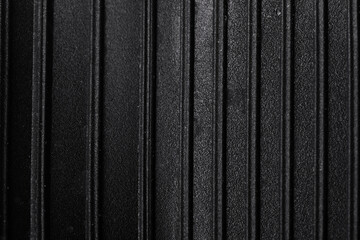 Close-up of black surface featuring evenly spaced vertical ridges, creating a modern, minimalist textured background for versatile commercial design use.