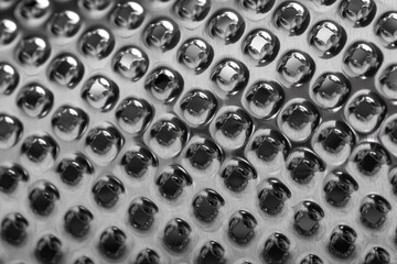 Close-up of reflective metallic surface with repeating rounded shapes, creating a modern abstract texture ideal for backgrounds and design projects.