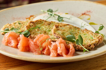 delicious smoked salmon with vegetable fritters, closeup of salmon paired with zucchini bites and herbs