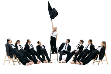 Business woman raising jacket triumphantly above group expressing bold confidence. Concept of leadership victory, body in motion, empowerment, individuality and creative workplace storytelling.