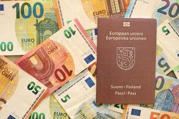 Finland passport lies on big amount of euro money banknotes close up. Rich life and travel in Europe concept