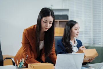 Asian female entrepreneurs coordinating product handover at an e-commerce office, preparing parcels for shipping logistics while collaborating professionally to manage online business operations