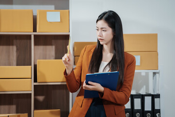 Asian female entrepreneurs coordinating product handover at an e-commerce office, preparing parcels for shipping logistics while collaborating professionally to manage online business operations