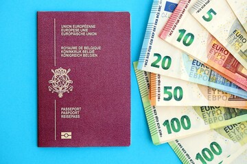 Belgium passport lies with euro money banknotes on blue background close up. Salary and pension in...