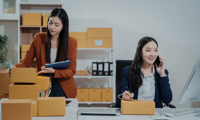 Asian female entrepreneurs coordinating product handover at an e-commerce office, preparing parcels for shipping logistics while collaborating professionally to manage online business operations