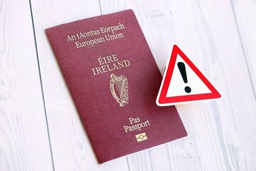 Ireland passport with exclamation sign on white wooden background close up. Problems with...
