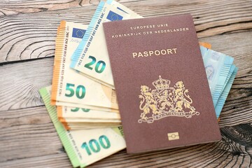 Netherlands passport lies with euro money banknotes on wooden background close up. Cash and...