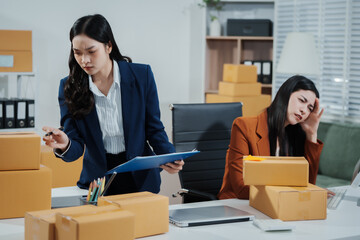 Two young Asian business woman stressed over poor sales, struggling with e-commerce order management, inventory, and logistics issues, showing visible frustration and pressure while handling parcels