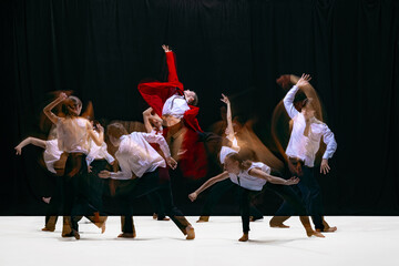 Red-jacket performer lifted mid-air as dancers swirl around in layered motion blur. Concept of expressive stage movement, kinetic storytelling, emotional choreography and contemporary performance.