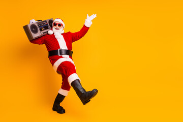 Joyful Santa in a red costume with a boombox dancing yellow background Christmas campaigns holiday...