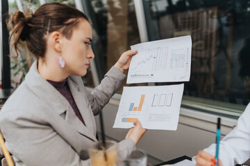 A professional examining charts and documents representing financial data and business progress in a meeting.
