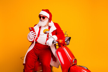 Santa on a bright red scooter with a phone in hand smiles for Christmas and holiday season promotion