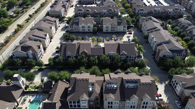 Clubhouse and fenced pool in modern apartment complex with lounge seating, pitched roofs, brick accents, organized driveway, walking path. Highway with trees, green zones in Denton County, Texas