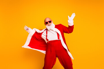 Santa in red costume with cape dances against yellow background with white beard and joyful pose for Christmas promotion