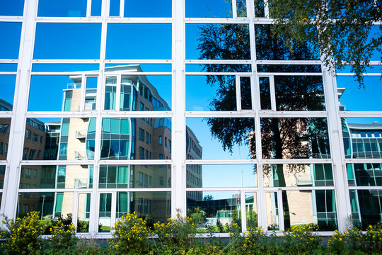 Office buildings and modern architecture interact through reflections on a glass facade, expressing geometry, clean lines, corporate tone and contrast in a clear commercial narrative