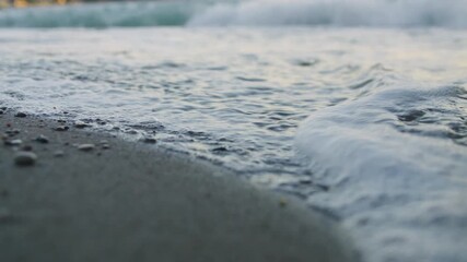 Close-up of gentle foaming sea waves lapping onto a beach. Low angle view. Montenegro.