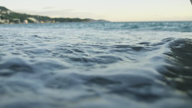 Close-up of gentle foaming sea waves lapping onto a beach. Low angle view. Montenegro.
