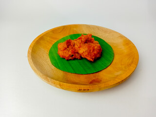 Dadar Jagung, Indonesia corn fritters, served on a round banana leaf on a wooden plate, isolated on a white background.