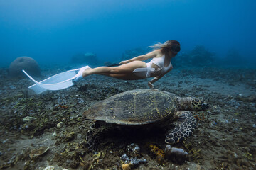 Woman glides with sea turtle underwater, marine life in sea