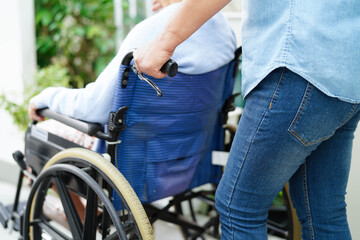 Caregiver help Asian elderly woman disability patient sitting on wheelchair in hospital.