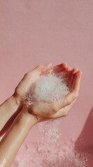 Fototapeta premium Soft bubbles rest gently in outstretched hands, creating a serene contrast against a smooth pastel pink backdrop. This scene captures a moment of fun and tranquility