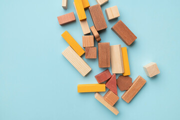 Montessori style cubes game for toddlers flat lay top view. Wooden children's construction set blocks of different shapes natural colors on blue background. Concept of learning and education