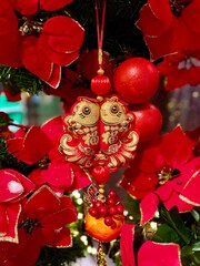 Vibrant red holly flowers decorations featuring a traditional fish ornament, creating a festive atmosphere for celebrations and cultural festivities. Vertical background 