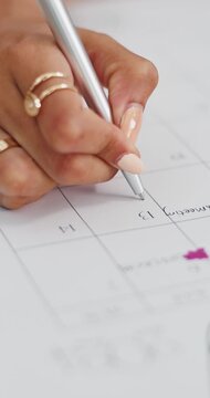 Woman, hands and writing in calendar for planning, monthly administration or appointment reminder. Female person, date or timetable notes in home for task priority, time management or personal goals.
