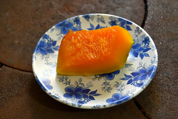 boilde pumpkin in a white blue flowery plate on black metallic background