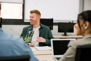 Smiling man collaborating with diverse colleagues in modern office meeting