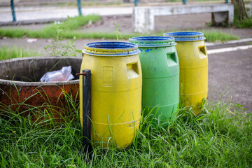 Colorful outdoor trash bins next to a sidewalk in a city park, Urban trash and recycling
