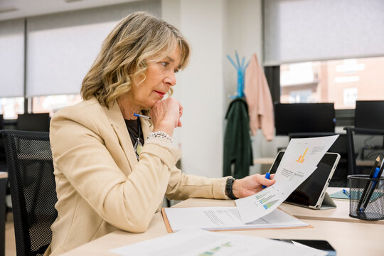 Mature businesswoman analyzing business data reports in office