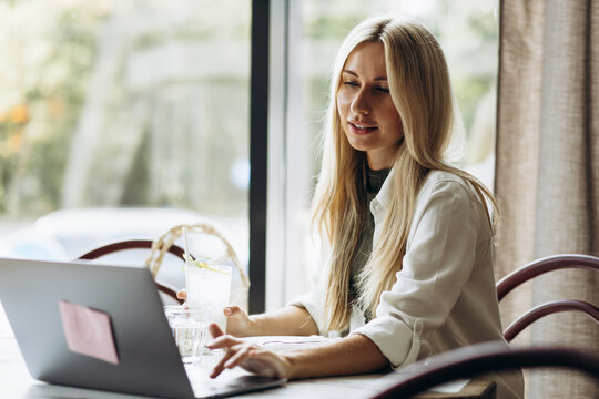Young woman sitting in a cafe and working and shopping online on a laptop - Powered by Adobe
