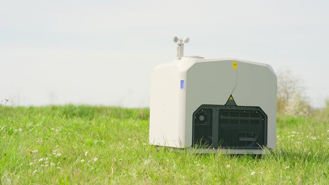 A drone launch box sits on a grassy field, equipped with technology and sensors from which a drone can be deployed.