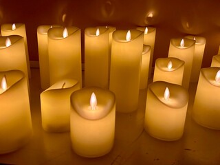 Softly glowing artificial candles arranged artistically on a surface, creating a warm ambiance with flickering flames, ideal for relaxation and romantic settings, enhancing peaceful environments