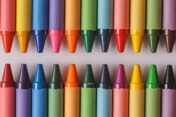 Two rows of colorful crayons viewed from above colored pencils