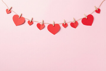 Valentine’s Day heart garland on pastel pink background with copy space.