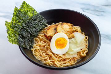 Ramen with egg noodles, char siu chicken, and fresh pickles, in a savory broth on a light background