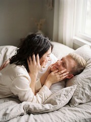 Tenderness morning moment of a loving couple cuddling softly in bed by the window.