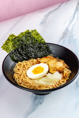 Ramen with egg noodles, char siu chicken, and fresh pickles, in a savory broth on a light background